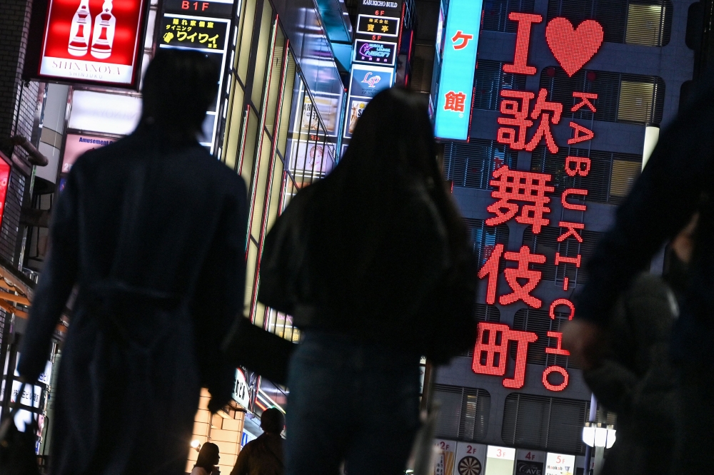 This photo taken on March 31, 2025 shows people walking down a street by the ‘I love Kabukicho’ neon sign in the red-light entertainment area of Kabukicho in the Shinjuku district of Tokyo. ‘Sex tourism’ in other Asian countries is well established, but the young women standing waiting around a Tokyo park near the Kabukicho entertainment district every night suggest that it’s coming out of the shadows in Japan too. — AFP pic