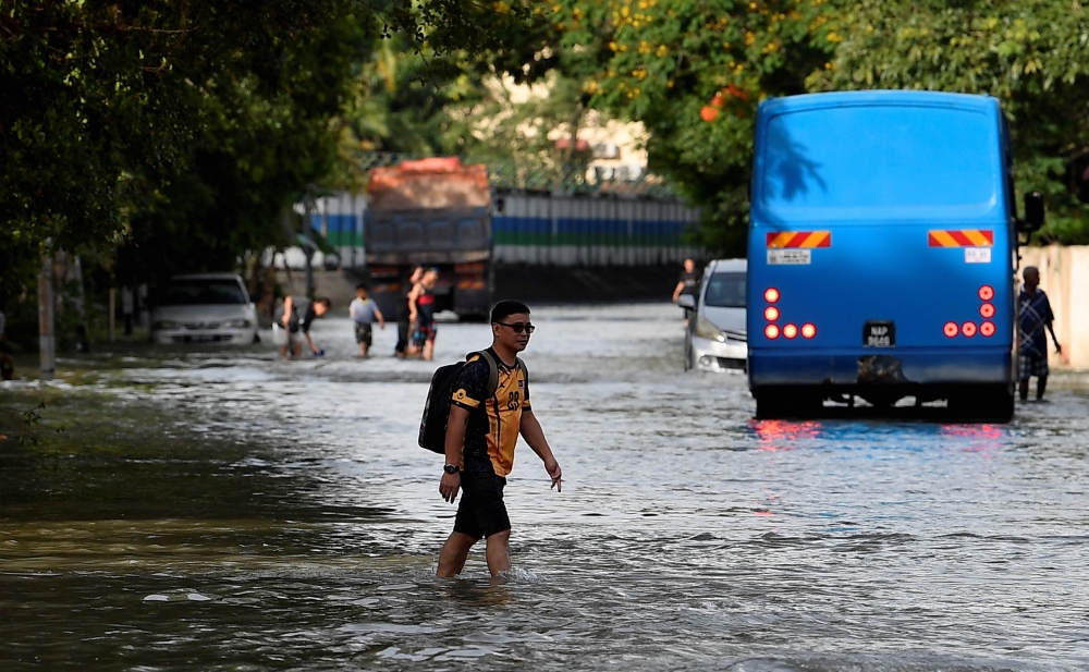 Residents of Taman Sri Muda wade through floodwaters following a flash flood in Section 25, Shah Alam. — Bernama pic