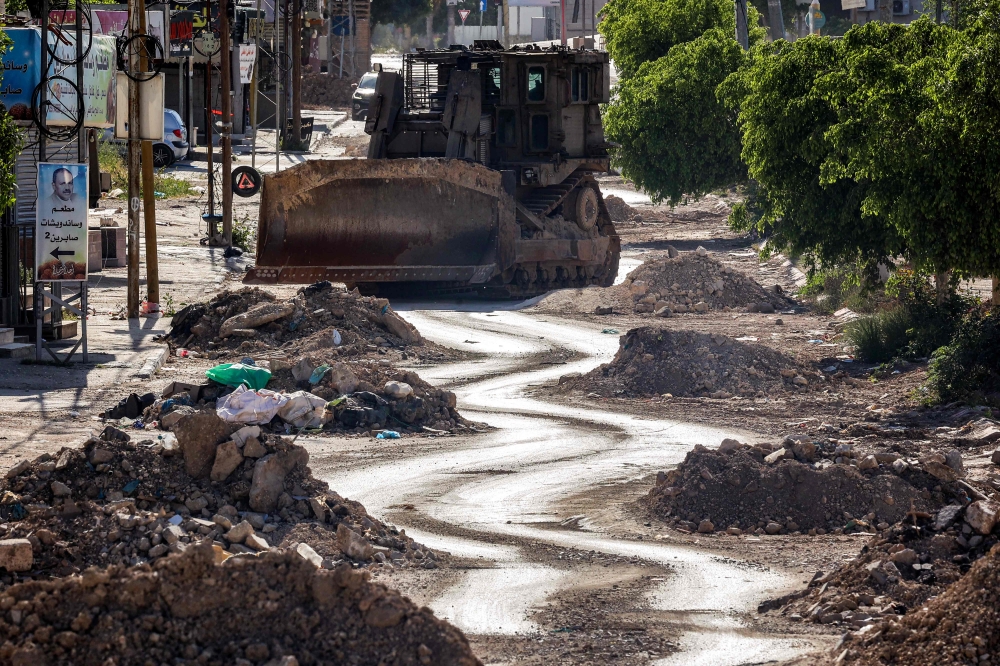 An Israeli military bulldozer is pictured along a partially-demolished road during an army operation in the Palestinian refugee camps in Tulkarem in the northwest of the occupied West Bank April 16, 2025. — AFP pic