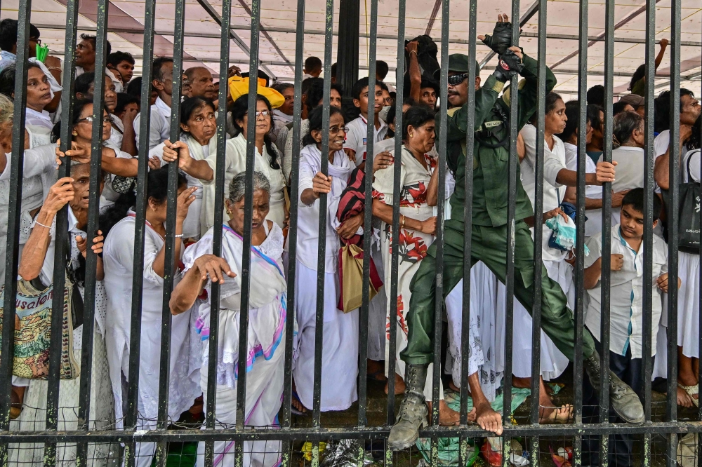 A military official (right) tries to help devotees avoid chaos during a gathering for a public exposition of the sacred Tooth relic of the Buddha at the Temple of the Tooth in Kandy April 18, 2025. Tens of thousands of pilgrims thronged Sri Lanka's holy city of Kandy on April 18 at the start of a rare display of a prized Buddhist relic, triggering traffic chaos and public protests. — AFP pic