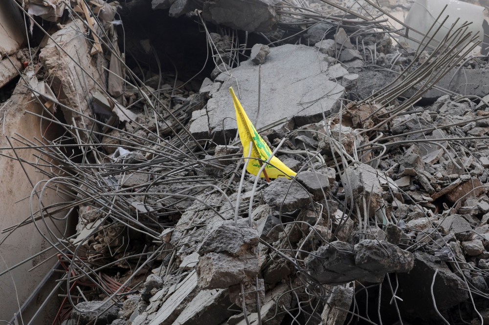A Hezbollah flag is placed in rubble on site of damaged buildings in Beirut. Lebanese President Joseph Aoun said today that disarming the Iran-backed Hezbollah group was a ‘delicate’ matter whose implementation required the right circumstances, warning that forcing the issue could lead the country to ruin. — AFP pic