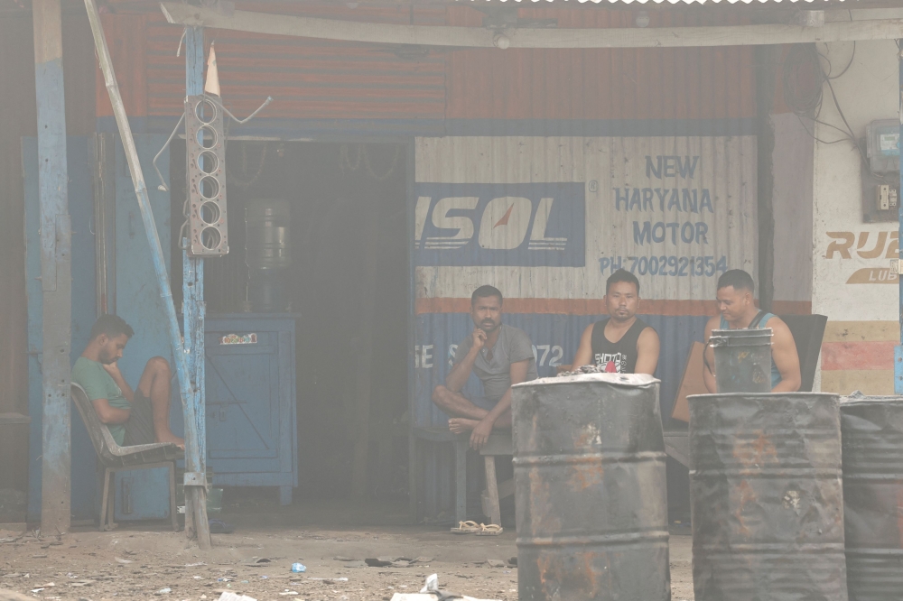 People sit outside a truck repair shop in the town of Brynihat, ranked world’s most polluted metropolitan area by Swiss Group IQAir, in India, March 29, 2025. — Reuters pic