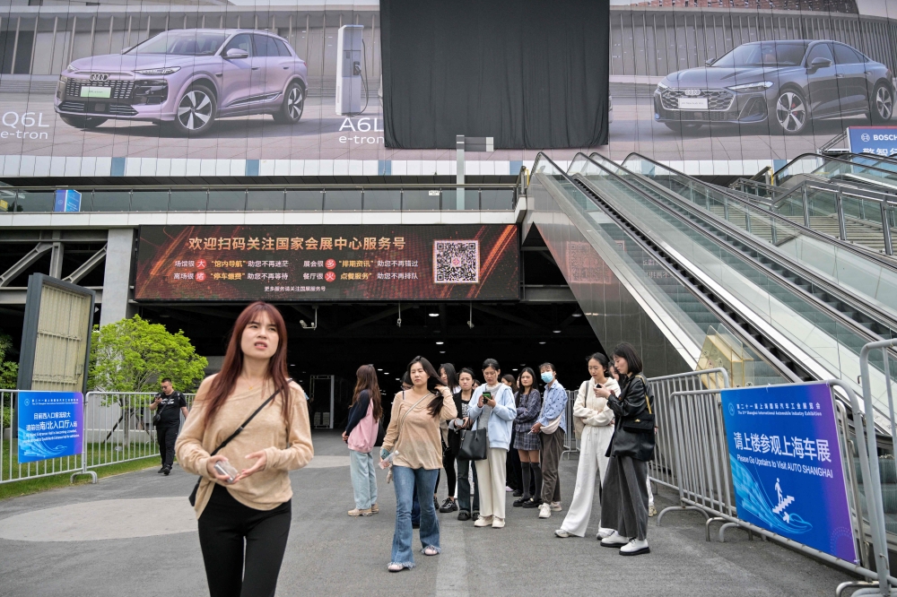 People look on outside the National Exhibition and Convention Centre, venue for the upcoming 21st Shanghai International Automobile Industry Exhibition, in Shanghai April 21, 2025. — AFP pic