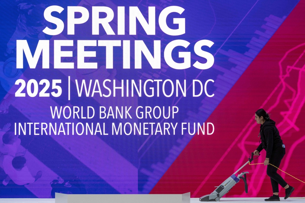A woman vacuums the stage ahead of the curtain raising speech at the International Monetary Fund/World Bank Spring Meetings in Washington, DC April 17, 2025. The World Bank and International Monetary Fund's Spring Meetings kick off on April 14, with the Bank keen to promote its agenda to drive job creation in developing and emerging market economies. — AFP pic