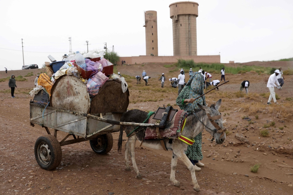A woman transporting rubbish in the a donkey-pulled cart looks on, as volunteers, including tourists, take part in a desert cleaning campaign during the Nomads Festival in Mhamid El-Ghizlane in Morocco’s southern Sahara desert on April 12, 2025. — AFP pic 