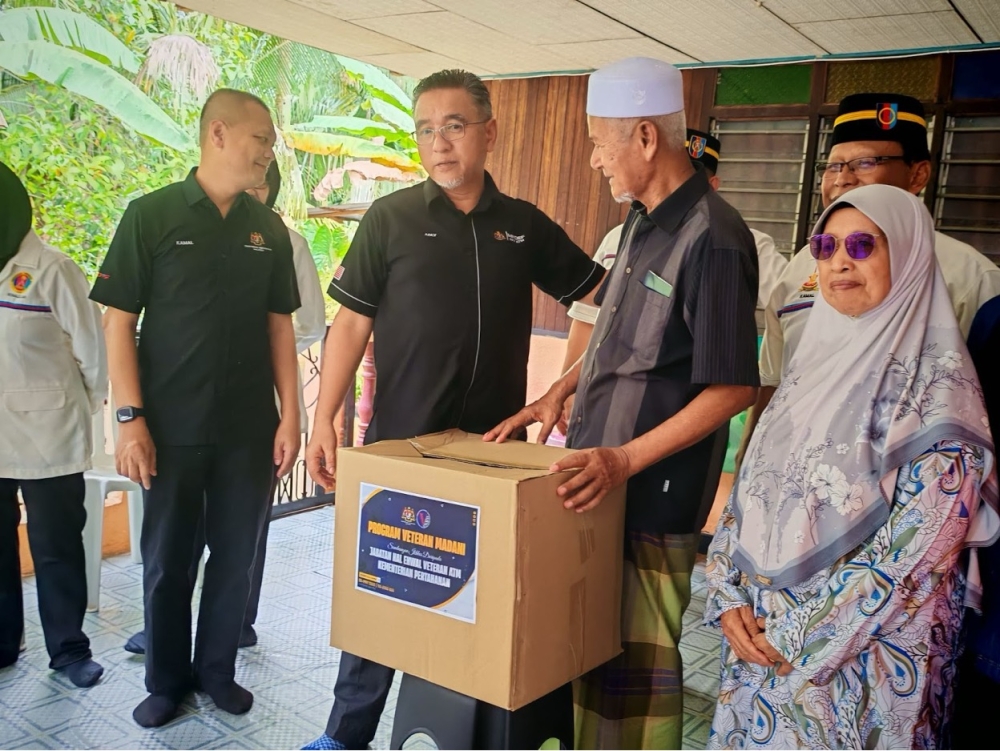 Deputy Defence Minister Adly Zahari (middle) presenting some aid to Staff Sergeant (right) Hasan Nayan at his home in Kampung Tengah, Pasir Panjang.