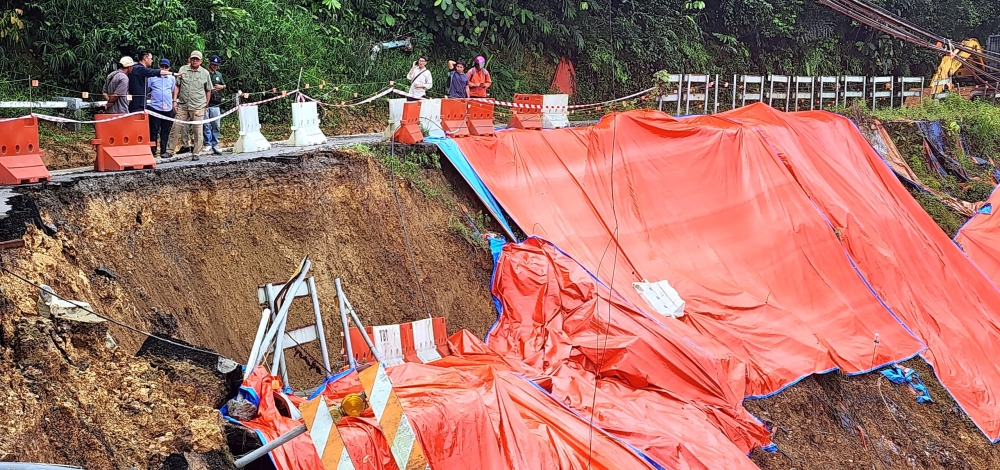 Joniston inspects the damaged road. — The Borneo Post pic