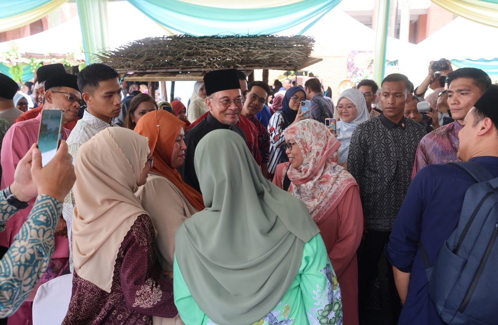Prime Minister Datuk Seri Anwar Ibrahim (centre) mingles with guests at the 2025 Madani Hari Raya celebration hosted by the Home Ministry (KDN) at the Setia Perkasa Complex here today. — Bernama pic