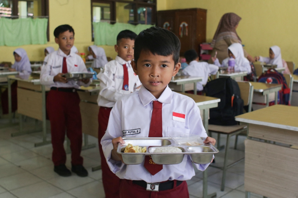Students receive lunch plates on the first day of a free-meal programme at Kedung Badag 1 State Elementary School in Bogor, West Java. — AFP
