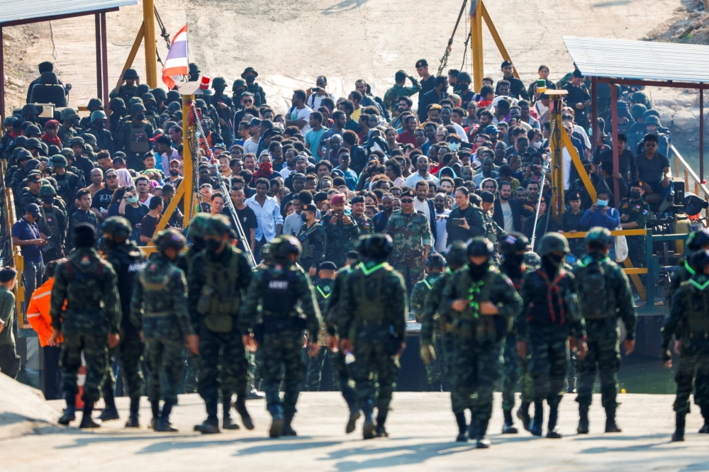 File picture of multinational victims of scam centres, who were tricked or trafficked into working in Myanmar, stand on a vessel floating towards the Thai side of border via Moei River in Phop Phra District, Tak province, Thailand. — Reuters pic