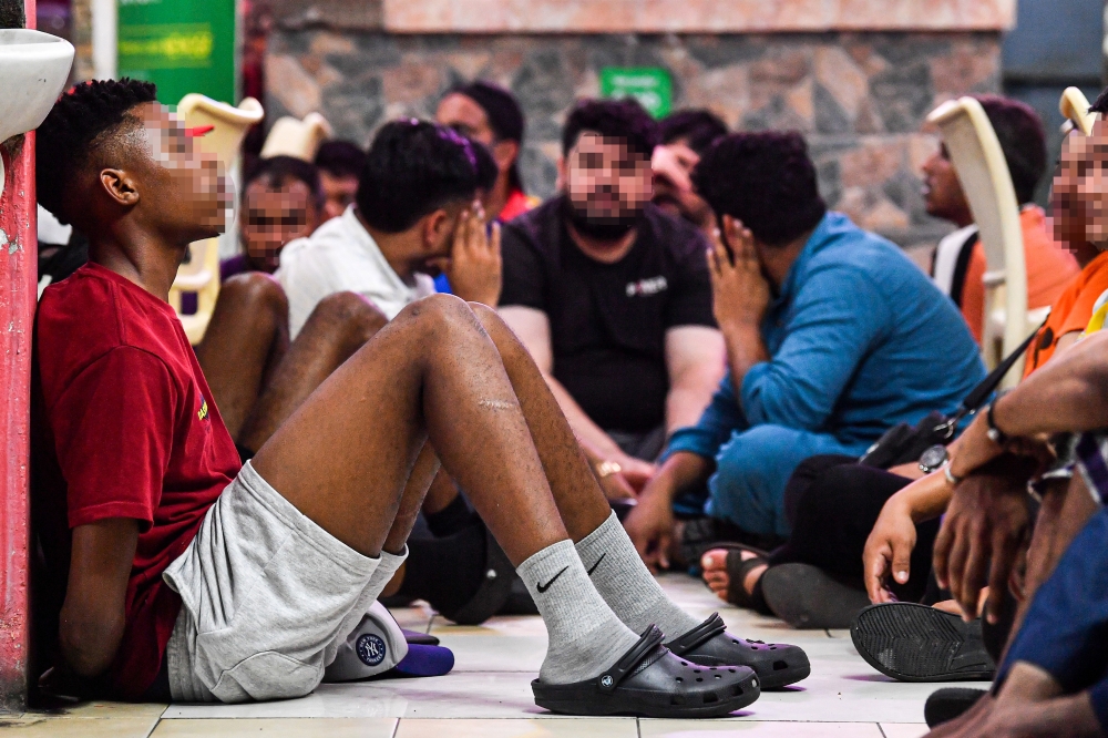 Foreign nationals from various countries react as they are detained for document inspection during an integrated operation by the Immigration Department, Labour Department and Civil Defence Force at Jalan Desa Palma, Nilai last night. — Bernama pic