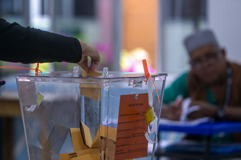 A voter places a ballot paper into the ballot box during the Ayer Kuning state by-election at the polling centre at Sekolah Menengah Agama Daerah Batang Padang, Tapah today. — Bernama pic