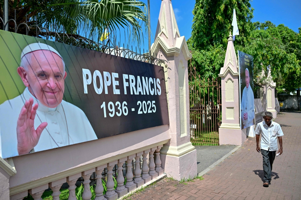 A man walks past All Saints' Church with portraits of the late Pope Francis placed at the entrance, in Colombo April 26, 2025. — AFP pic