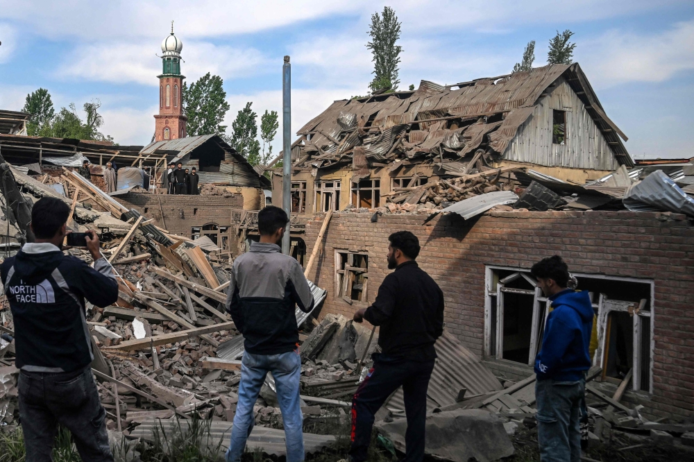 Neighbours gather near a demolished house related to the family of Ahsan Ul Haq Sheikh, who is suspected of involvement in the Pahalgam tourist attack. — AFP pic