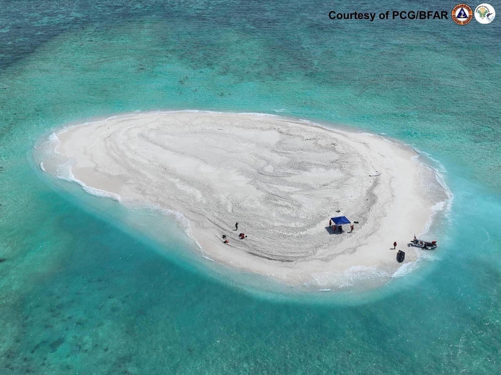 This handout photo taken on March 21, 2024 and received from the Philippine Coast Guard and Bureau of Fisheries and Aquatic Resources (PCG/BFAR) shows an aerial view of Philippine scientists inspecting Sandy Cay reef, near the Philippine-held Thitu Island, in Spratly Islands, in disputed waters of the South China Sea. — Philippine Coast Guard handout/AFP pic
