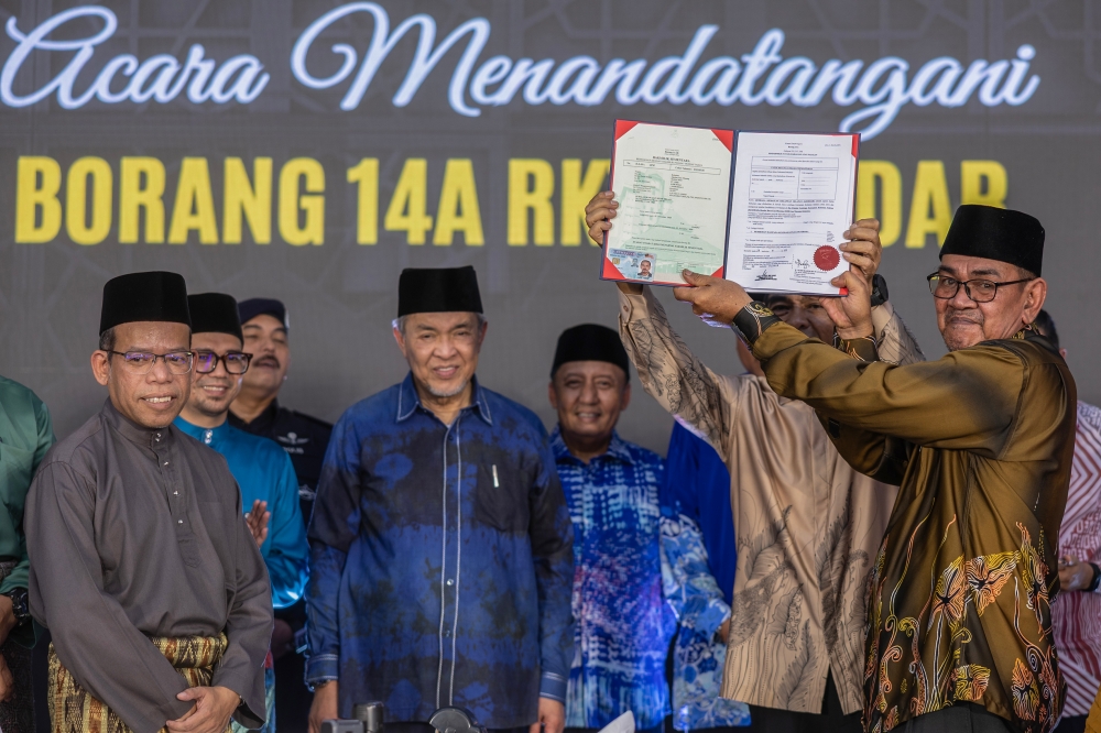 Deputy Prime Minister Datuk Seri Ahmad Zahid Hamidi with the head of settlers for the South Kelantan Development Authority (Kesedar) in Paloh 3, Hassan Salleh (right), after a symbolic handover of land grant ownership to Kesedar settlers at the Kampung Jerek Public Square in Gua Musang, April 28, 2025. — Bernama pic 