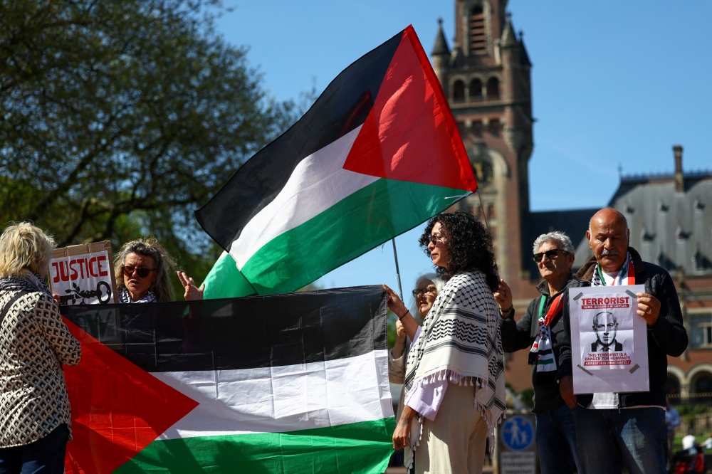 People hold Palestinian flags and placards outside The International Court of Justice (ICJ) on the day of a hearing in the ongoing case regarding Israel’s occupation of Palestinian territories, in The Hague, Netherlands, April 28, 2025. — Reuters pic 