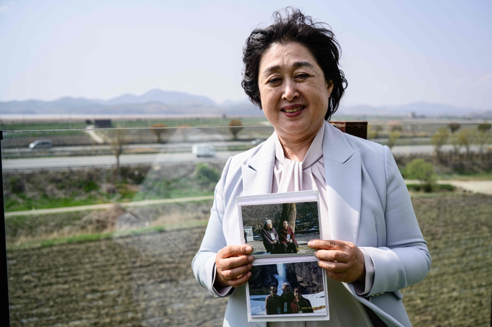 In this photo taken on April 24, 2025, Daonsoop cafe founder Lee Oh-sook poses while holding photos of her relatives with whom she visited Kaesong in North Korea in 2008 as a tourist, on the terrace of her establishment built less than two kilometres from the North Korean border in Paju, north of Seoul. — AFP pic