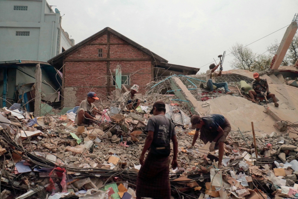 People sort through the rubble of a collapsed building in Mandalay on April 5, 2025, following the March 28 earthquake. — AFP pic