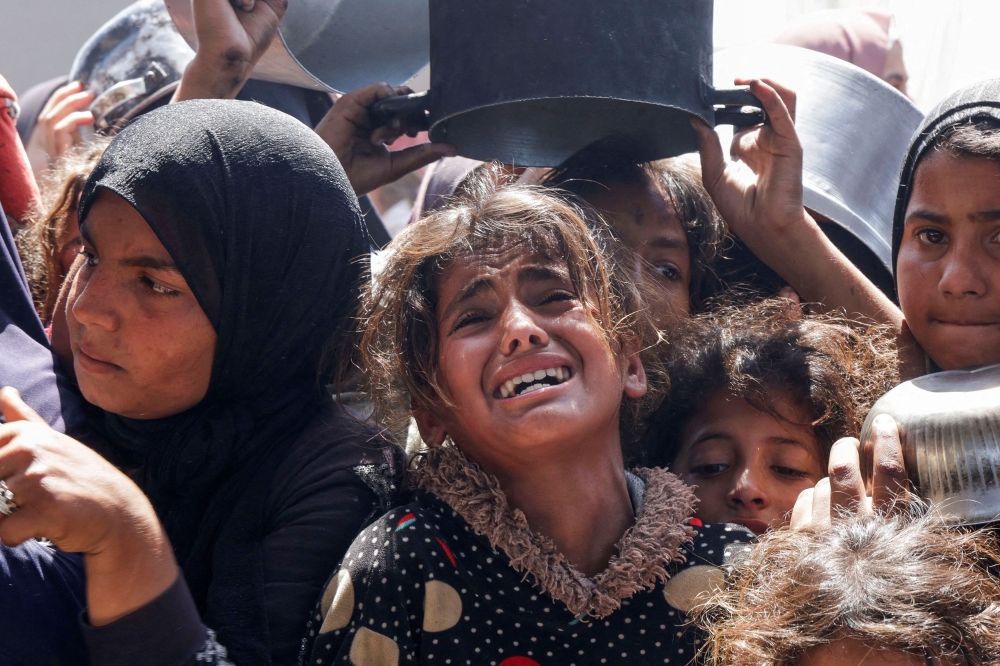 A Palestinian reacts as people gather to receive food cooked by a charity kitchen, in Khan Younis, southern Gaza Strip, April 29, 2025. — Reuters pic 