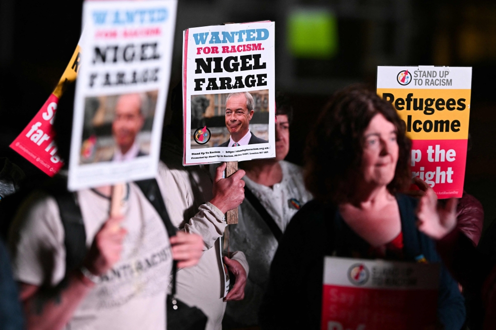 Protestors hold placards with leader of the British far-right Reform UK party Nigel Farage during a demonstration against the politician outside the count centre, at the DSBL stadium, in Widnes, north-west England, May 1, 2025, where the counting of ballots for the Runcorn & Helsby by-election is taking place. — AFP pic