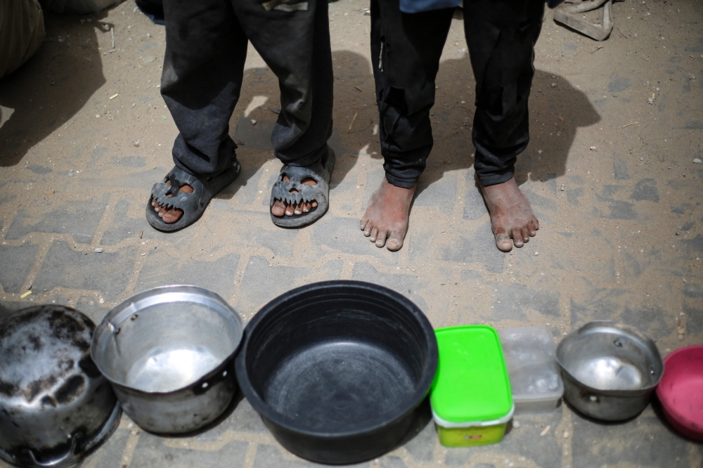 Palestinian children stand over empty containers at a food distribution centre in the Nuseirat camp for refugees, in the central Gaza Strip, April 30, 2025. — AFP pic