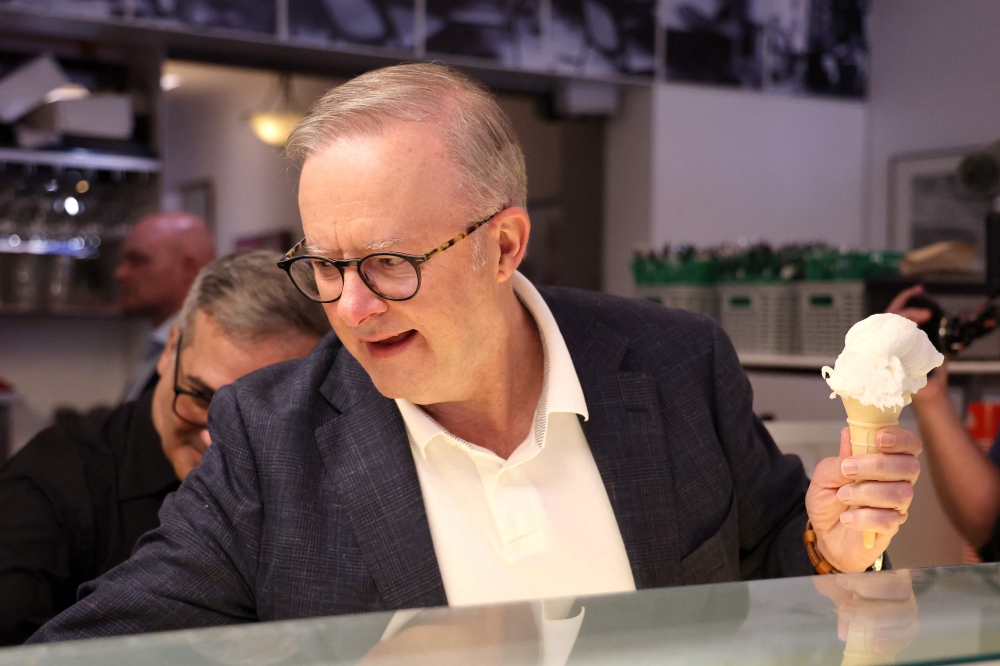 Australian Prime Minister Anthony Albanese scooping ice cream for journalists in a cafe he used to visit with his late mother. — AFP pic