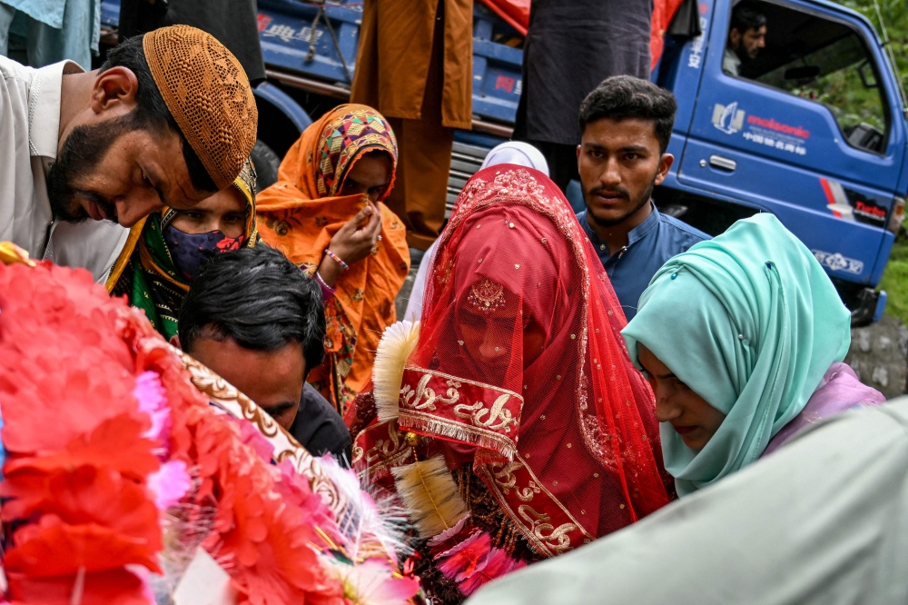 Kashmiri bride Rabia Bibi (centre) prepares to sit in a Doli, a traditional hand cart used to carry brides at weddings, as she leaves for the groom's house in Ashkot village on the Line of Control (LoC) in Neelum Valley, district of Pakistan-administered Kashmir, on May 3, 2025, following the ongoing border tensions between India and Pakistan after the Kashmir tourist attack. — AFP pic