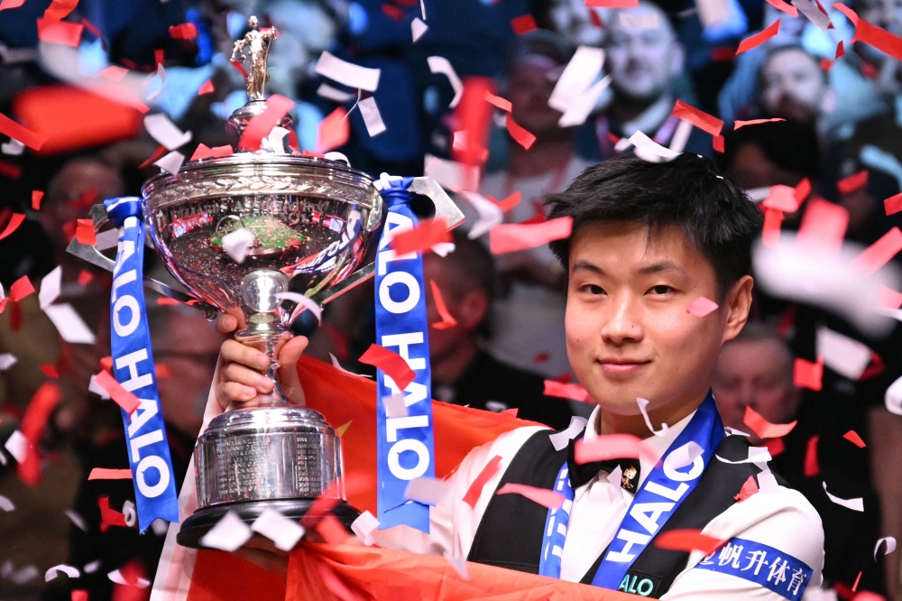 China's Zhao Xintong poses with the trophy after victory over Wales' Mark Williams in the World Championship Snooker final at The Crucible in Sheffield, northern England yesterday. — AFP pic