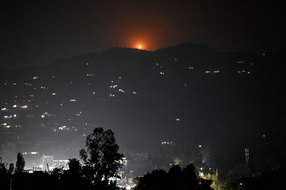 A flare goes up in air over the hill near main town of Poonch district today. — AFP pic