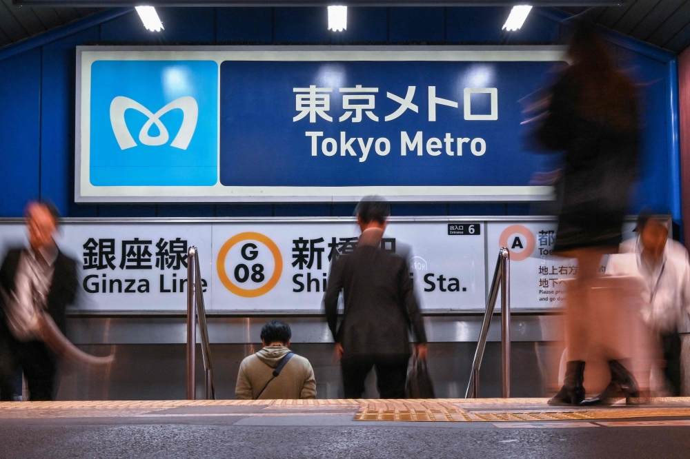 People walk past signs for the Tokyo Metro underground system inside Shimbashi station in central Tokyo in this file photo taken on October 21, 2024. A man was apprehended in Tokyo after an alleged knife attack on the subway system today that injured several people, Japanese media reported. — AFP pic