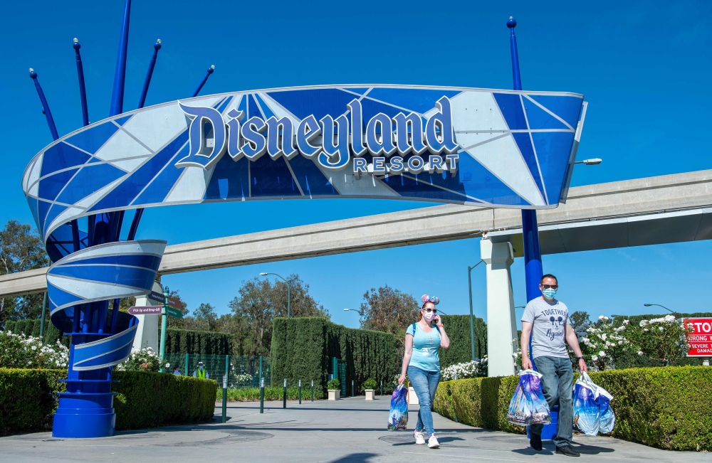 Visitors carrying Disney bags leave Disneyland on the day of the park's re-opening on April 30, 2021, in Anaheim, California, after it was closed in March 2020 due to the Covid-19 pandemic. — AFP pic