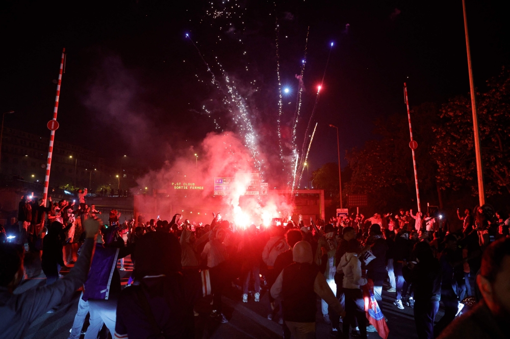 Paris Saint-Germain (PSG) supporters set off flares and fireworks as they block the highway near the Parc des Princes Stadium in Paris. — AFP pic