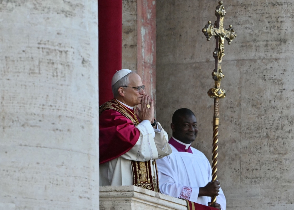 Newly elected Pope Leo XIV, Robert Francis Prevost (centre) gestures as he addresses the crowd from the main central loggia balcony of the St Peter's Basilica for the first time, after the cardinals ended the conclave, in The Vatican May 8, 2025. — AFP pic
