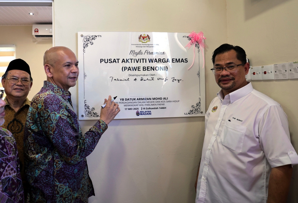 Domestic Trade and Cost of Living Minister Datuk Armizan Mohd Ali (centre) signs a plaque to symbolically officiate the opening of the Senior Citizens Activity Centre (PAWE) building in Benoni, Papar. — Bernama pic