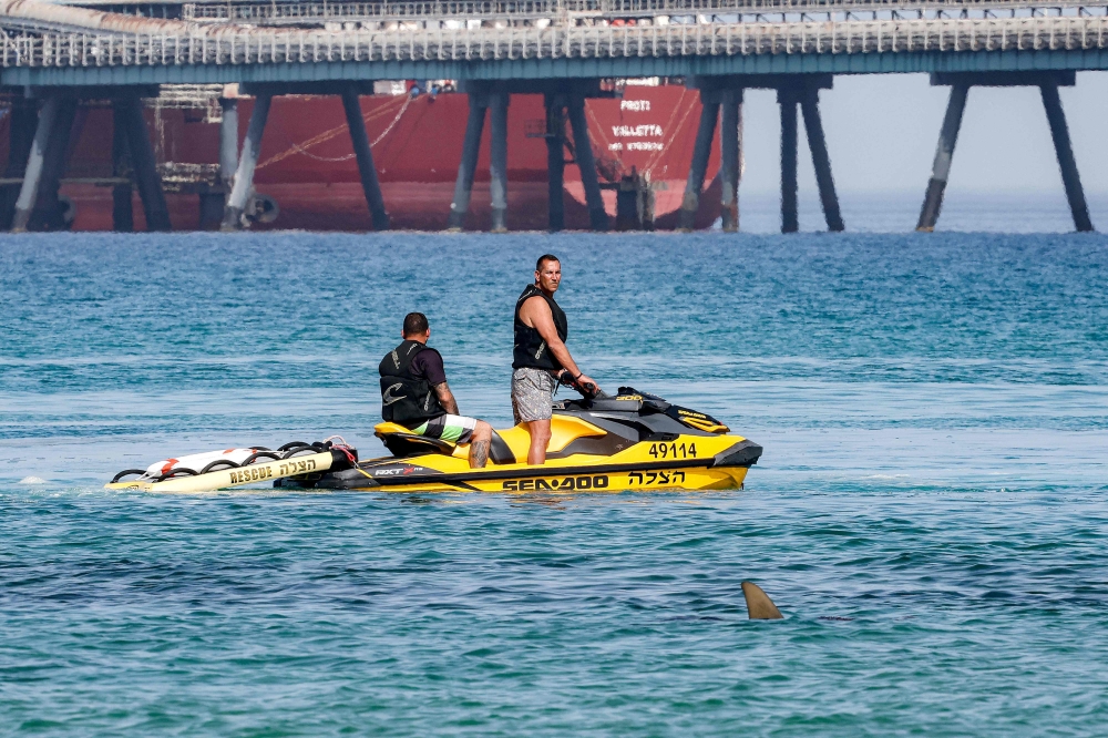A shark fin is pictured as Israeli rescue services aboard a personal watercraft search for a missing man in the Mediterranean sea waters off the pier of the port of Hadera on April 22. — AFP pic