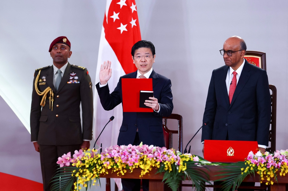 Lawrence Wong (centre) is sworn in as Singapore's Prime Minister as Singapore's President Tharman Shanmugaratnam (right) looks on during a swearing-in ceremony at the Istana in Singapore on May 23, 2025. — AFP pic