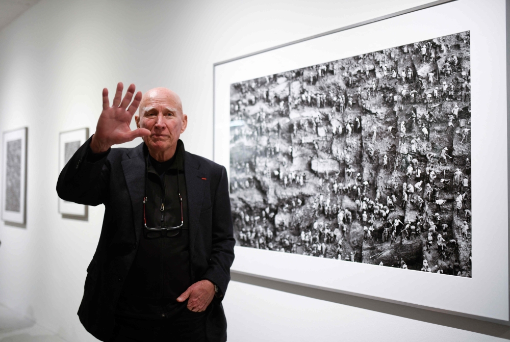 French-Brazilian photographer Sebastiao Salgado gestures as he stands in front of his work at the Bene Taschen gallery at his exhibition Gold in Cologne on February 6, 2020. — AFP pic