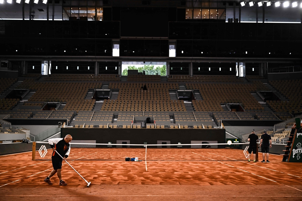 Staff members prepare the surface of the Court Philippe-Chatrier, ahead of French Open 2025 at the Roland Garros Complex in Paris May 21, 2025. — AFP pic