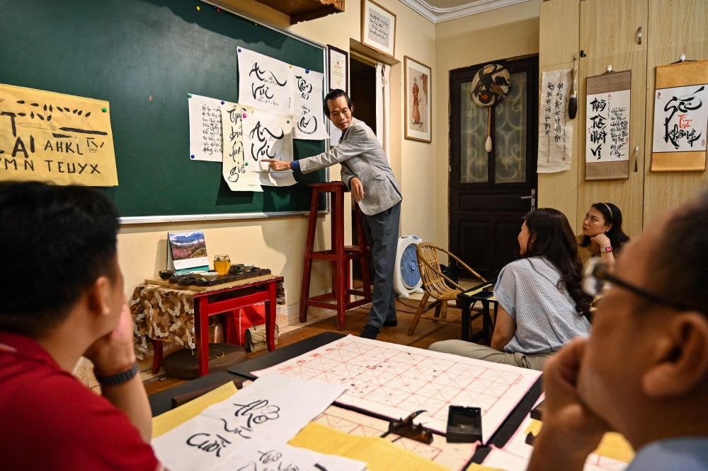 Calligrapher Nguyen Thanh Tung (centres) teaches students at his home in Hanoi May 15, 2025. — AFP pic