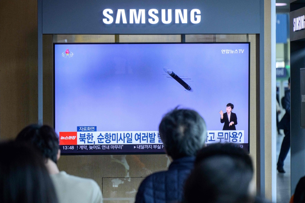People sit in front of a television as file footage of a North Korean missile launch is broadcast during the news, at a railway station in Seoul May 22, 2025.— AFP pic