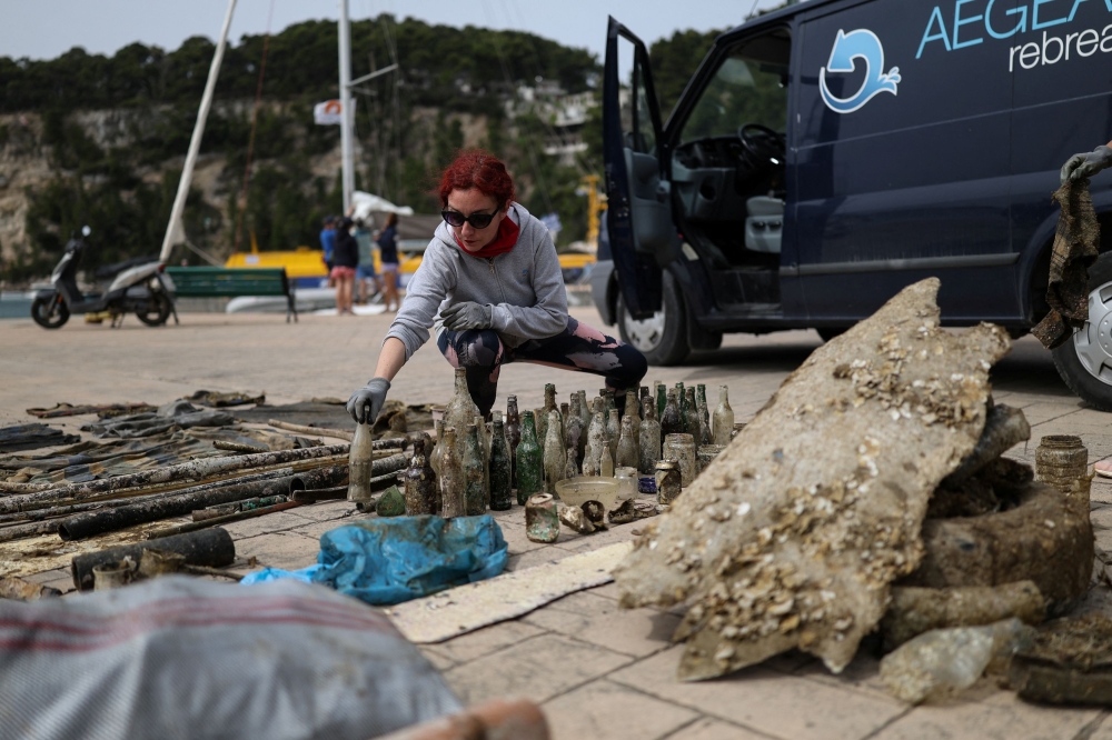A volunteer of the environmental group Aegean Rebreath arranges waste gathered from the bottom of the seabed of the port of Votsi, on the island of Alonissos, Greece, May 25, 2025. — Reuters pic