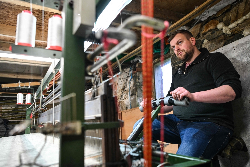 Harris Tweed weaver Alexander MacLeod works behind his weaving loom in his atelier at his home, on the Isle of Scalpay. — AFP pic