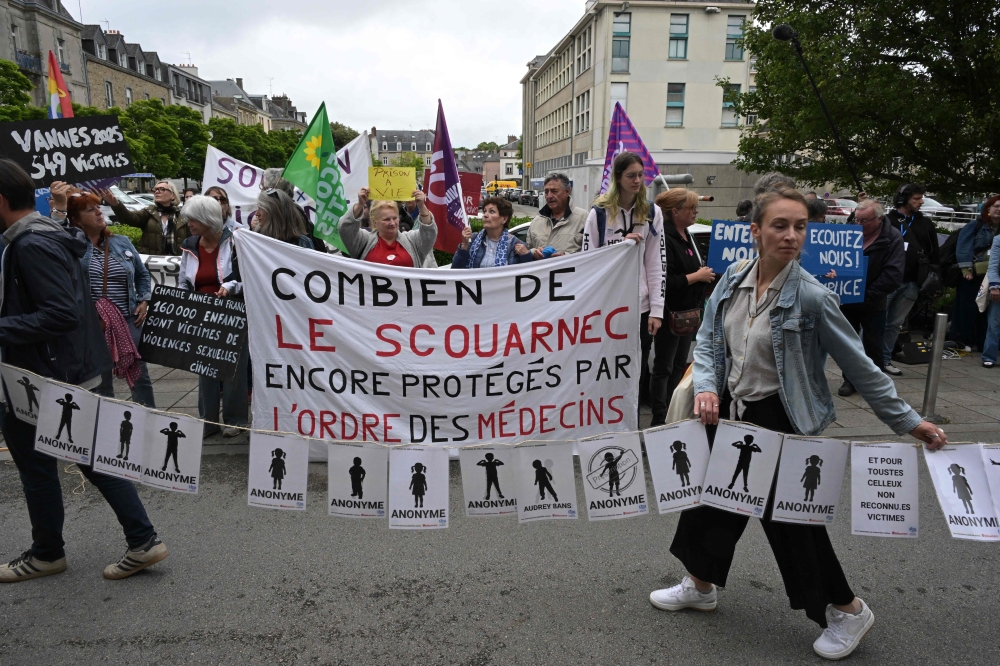 Protestors hold signs bearing the names of the victims and a banner reading ‘how many Le Scouarnec are still protected by the medical board’ (centre) during a May 28, 2025 solidarity demonstration with survivors of retired surgeon Joel Le Scouarnec’s trial for the sexual abuses of hundreds of children in Vannes, France. — AFP pic