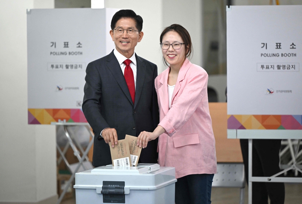 Kim Moon-soo (L), the presidential candidate for South Korea's conservative People Power Party, casts his ballot with his daughter (R) at a polling station during early voting for the presidential election in Incheon on May 29, 2025. — AFP pic
