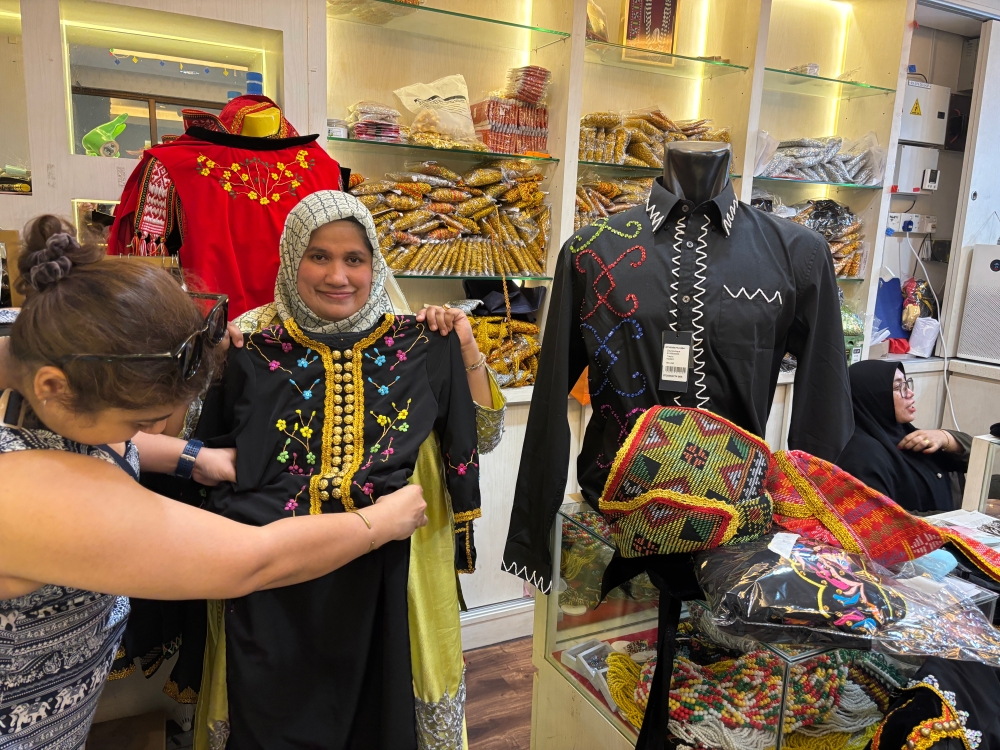 Asurah Karim (right), known for her traditional costumes, with one of her many multiracial clients. — Picture by Julia Chan