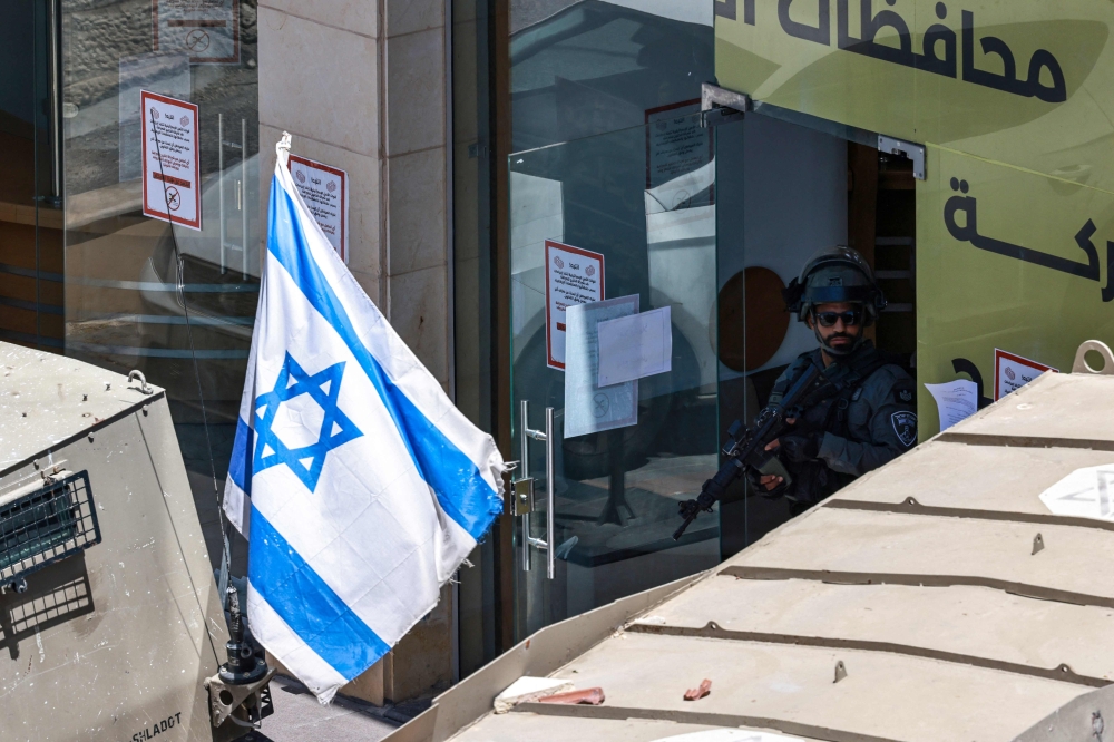 An Israeli army soldier stands guard during a raid on a currency exchange shop in Ramallah, in the occupied West Bank May 27, 2025. Israel will not allow a planned meeting in the Palestinian administrative capital of Ramallah, in the occupied West Bank, to go ahead, an Israeli official said today. — AFP pic