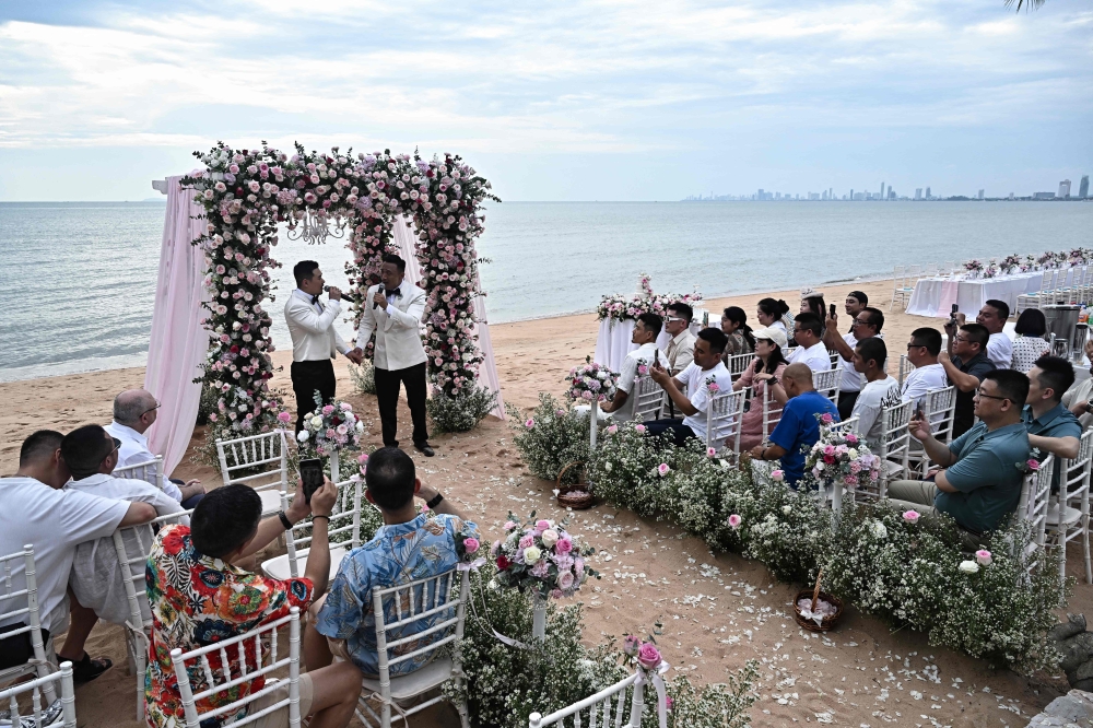 Chinese nationals Song Jihan (centre L) and Wang Zengyi (centre R) sing together during their wedding ceremony near Pattaya in Chonburi province on May 31. — AFP pic