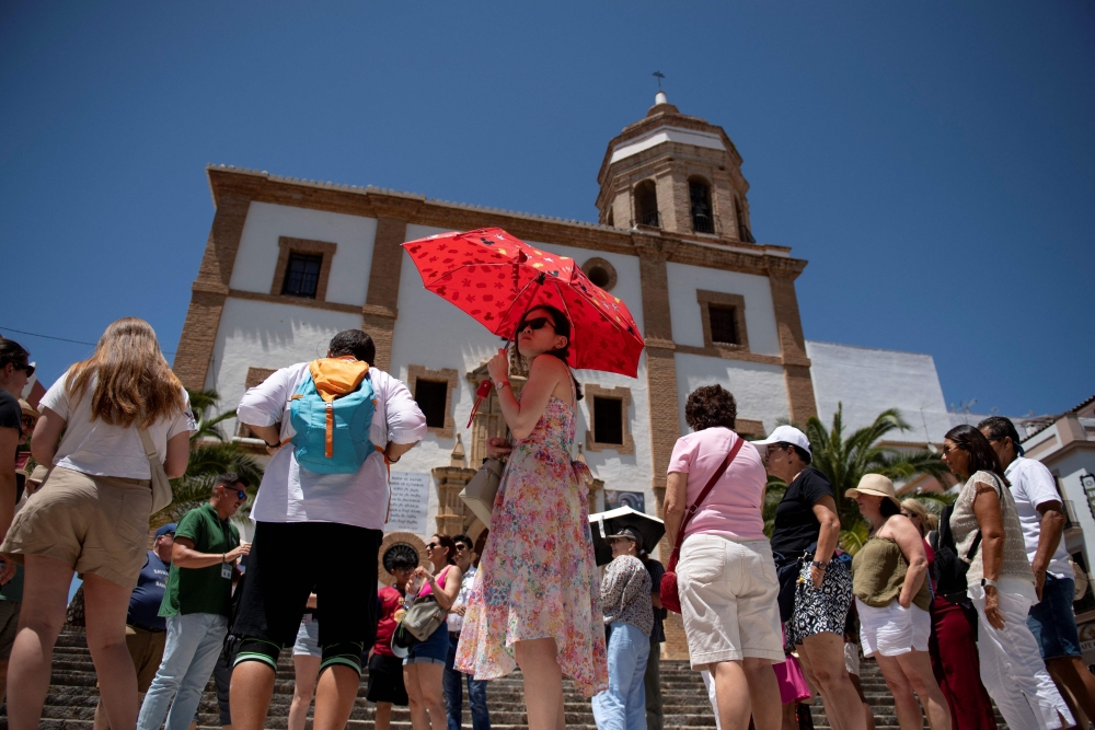 A woman hides from the sun with an umbrella in Ronda, southern Spain as the country faces the first heatwave of the season, on May 28, 2025. — AFP pic