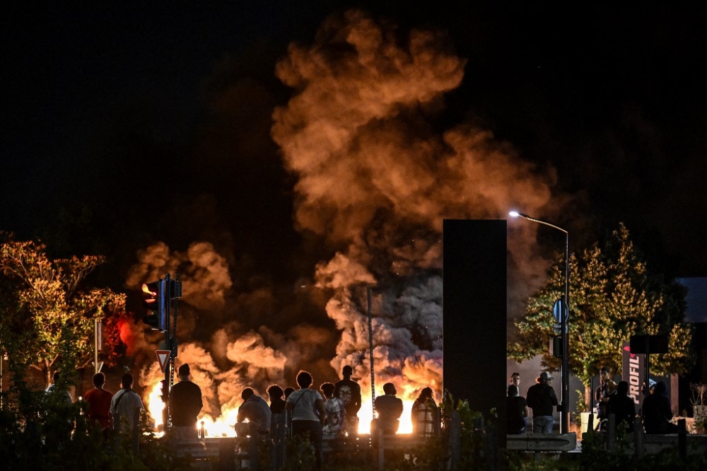 People look at burning tyres blocking a street in Bordeaux, south-western France on late June 29, 2023, during riots and incidents nationwide after the killing of a 17-year-old boy by a police officer's gunshot following a refusal to comply in a western suburb of Paris. — AFP pic